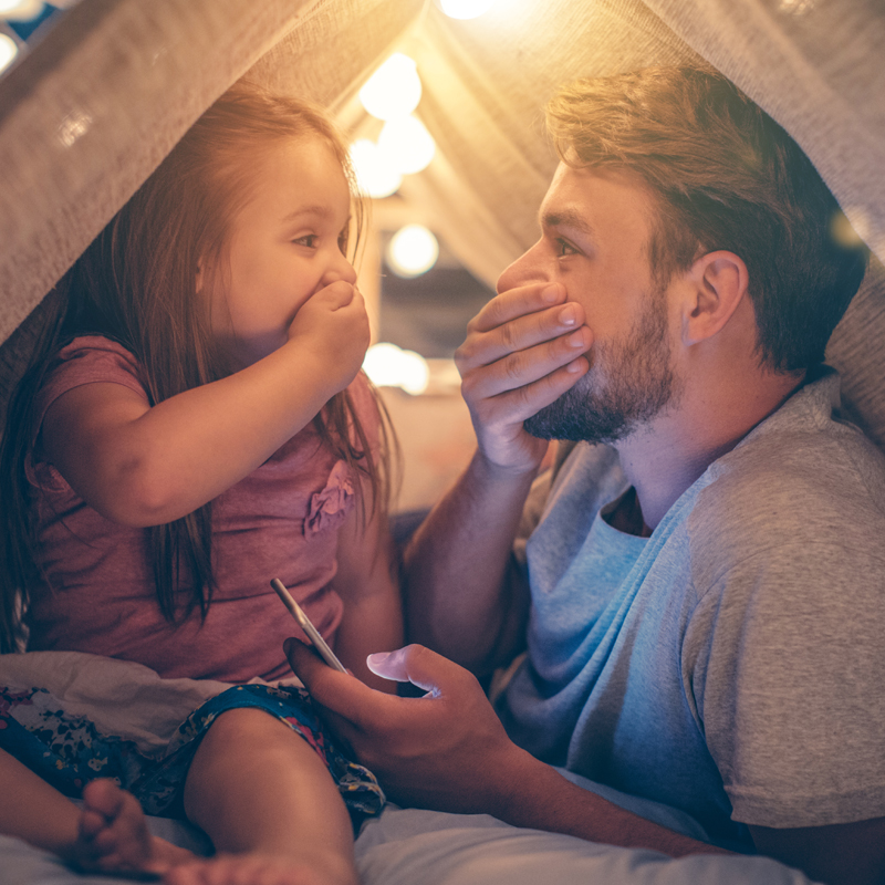 dad-and-daughter-covering-mouths-in-fort-800x800.jpg