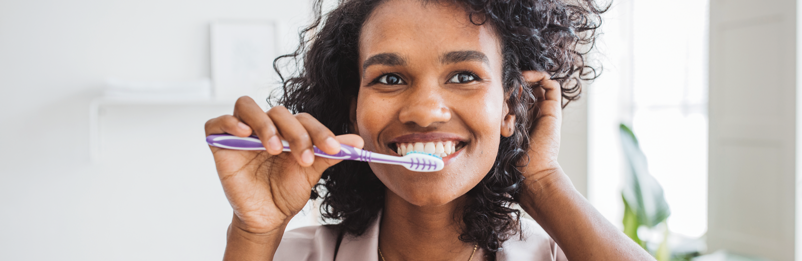 woman-smiling-brushing-teeth-1600x522.png