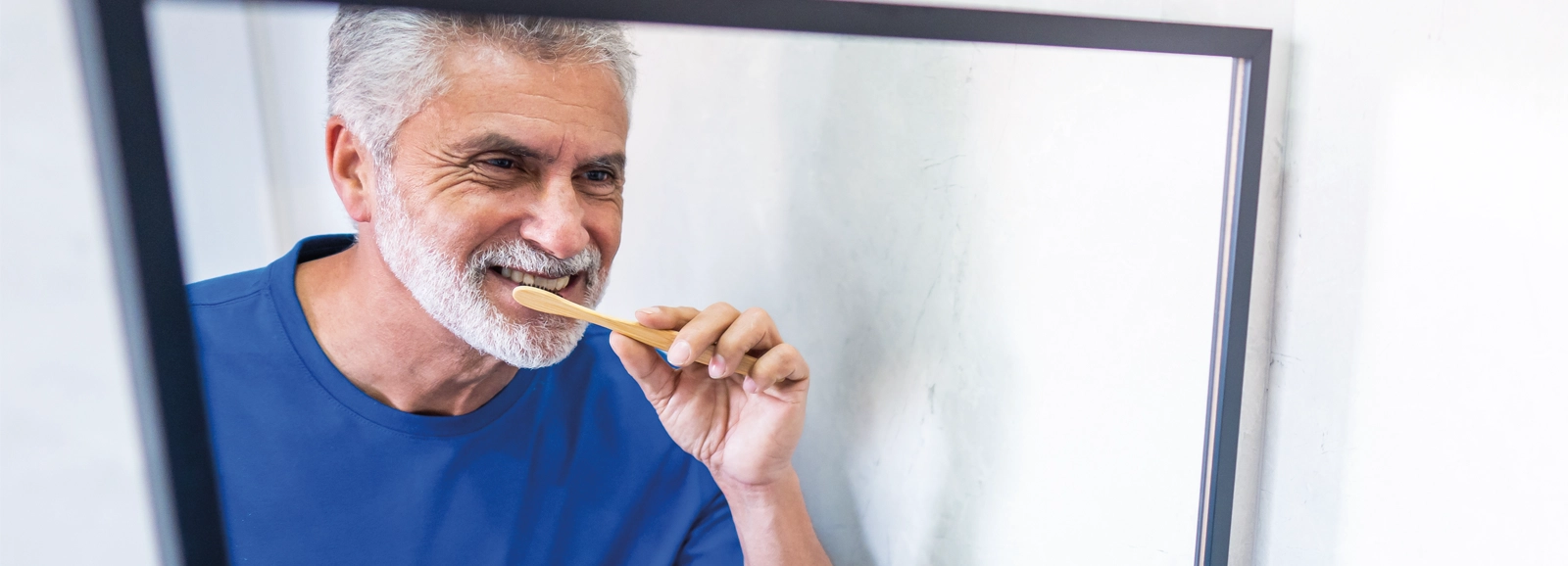 man-brushing-teeth-in-mirror-1600x578.webp