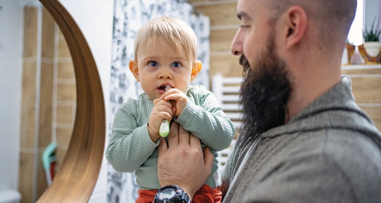 dad-holding-a-baby-brushing-his-teeth-752x400.webp
