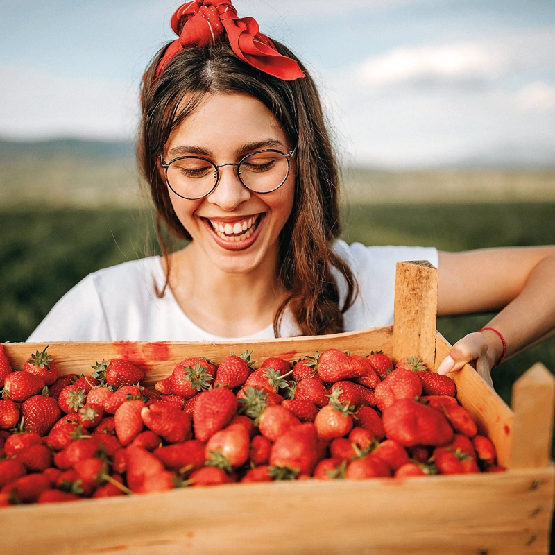 woman-smiling-looking-at-strawberries-800x800.webp