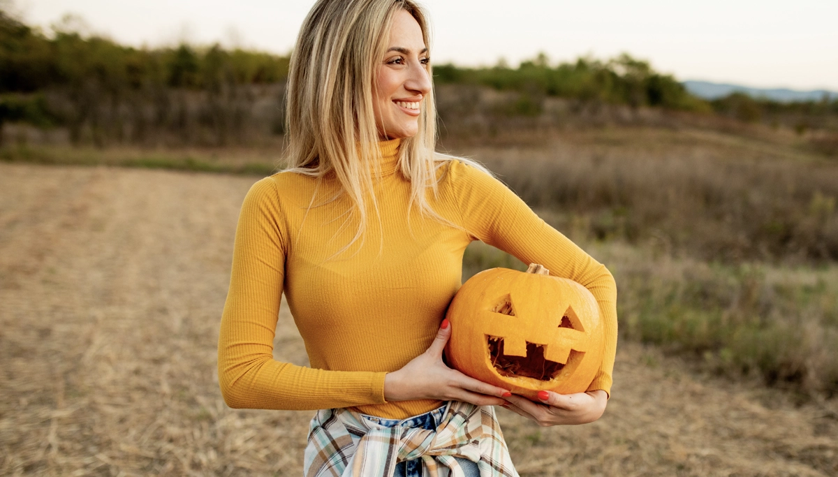 woman-smiling-holding-jack-o-lantern-1200x683.webp