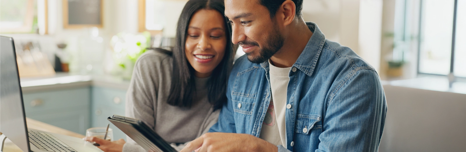 couple-smiling-while-looking-at-tablet-1600x522.webp