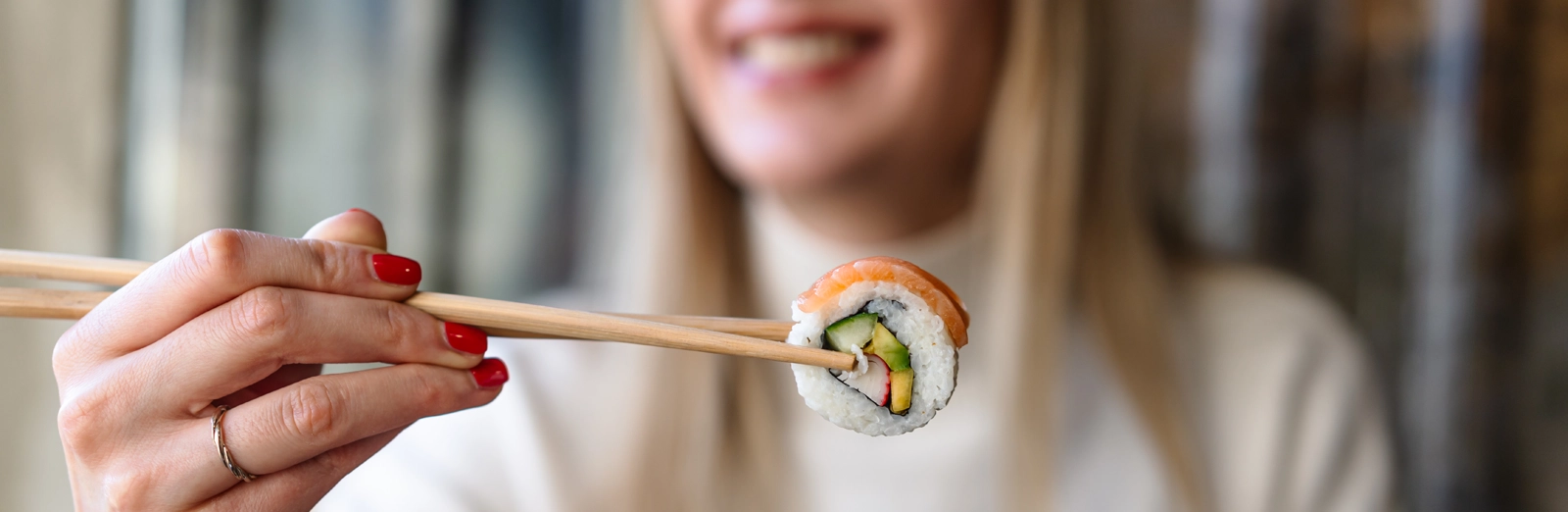 woman-holding-sushi-with-chopsticks-1600x522.webp