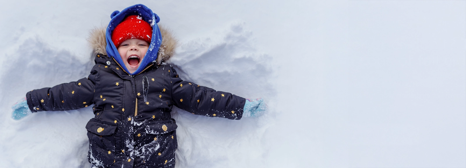 young-boy-laying-in-the-snow-1600x578.webp