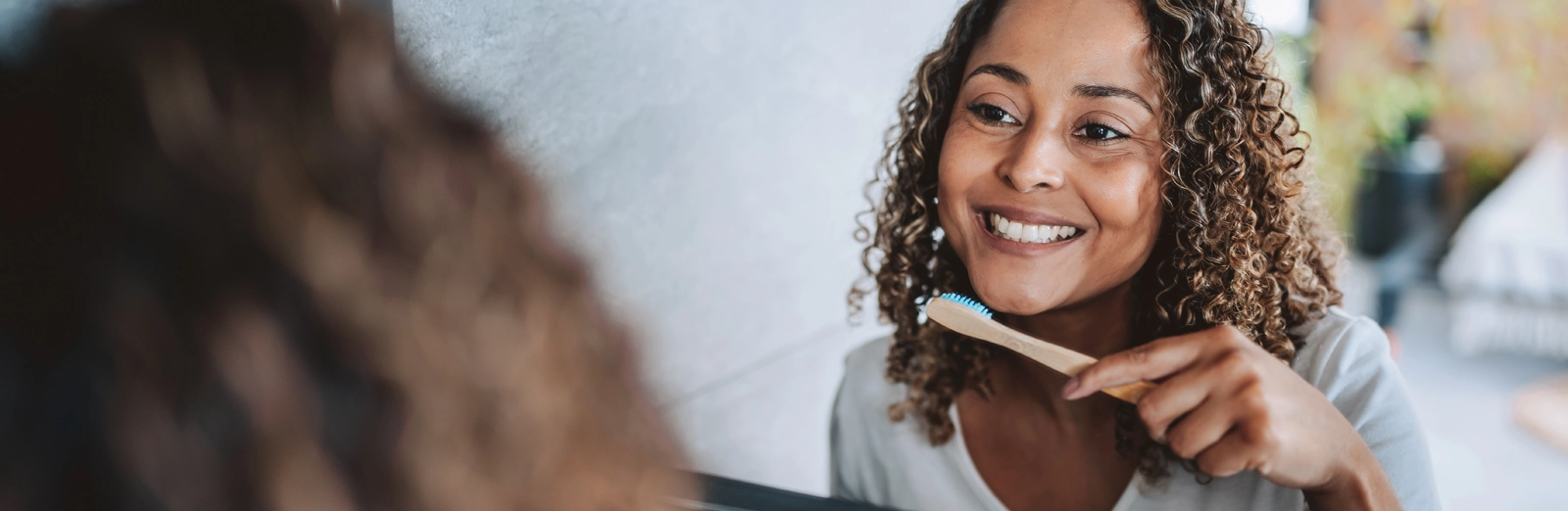 woman-smiling-while-brushing-teeth-1600x522.webp