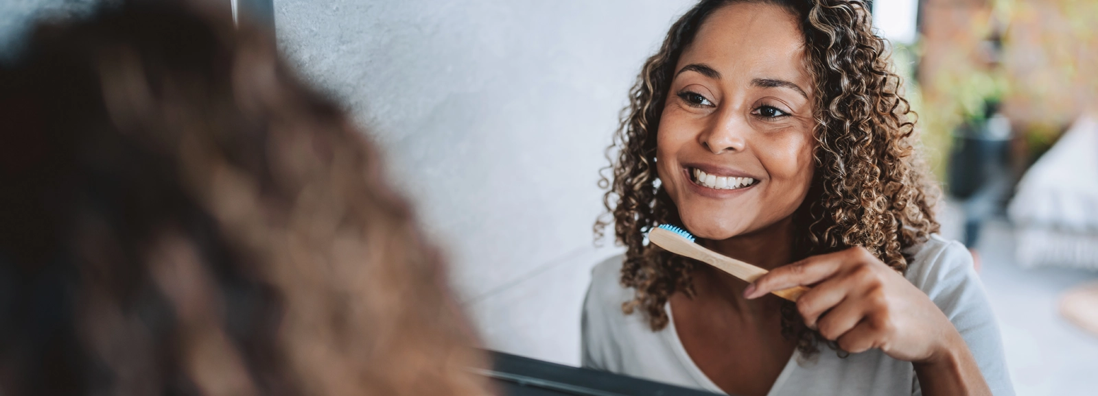 woman-smiling-while-brushing-teeth-1600x578.webp