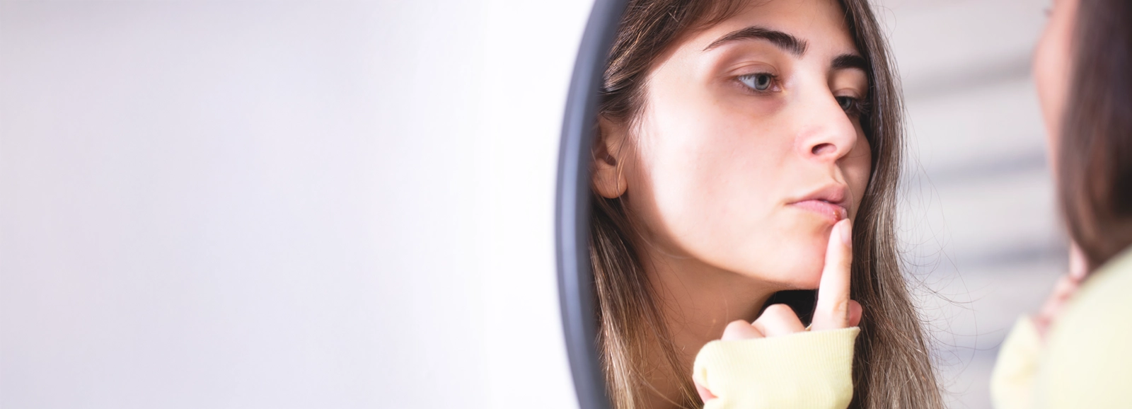 woman-looking-at-cold-sore-in-mirror-1600x578.webp
